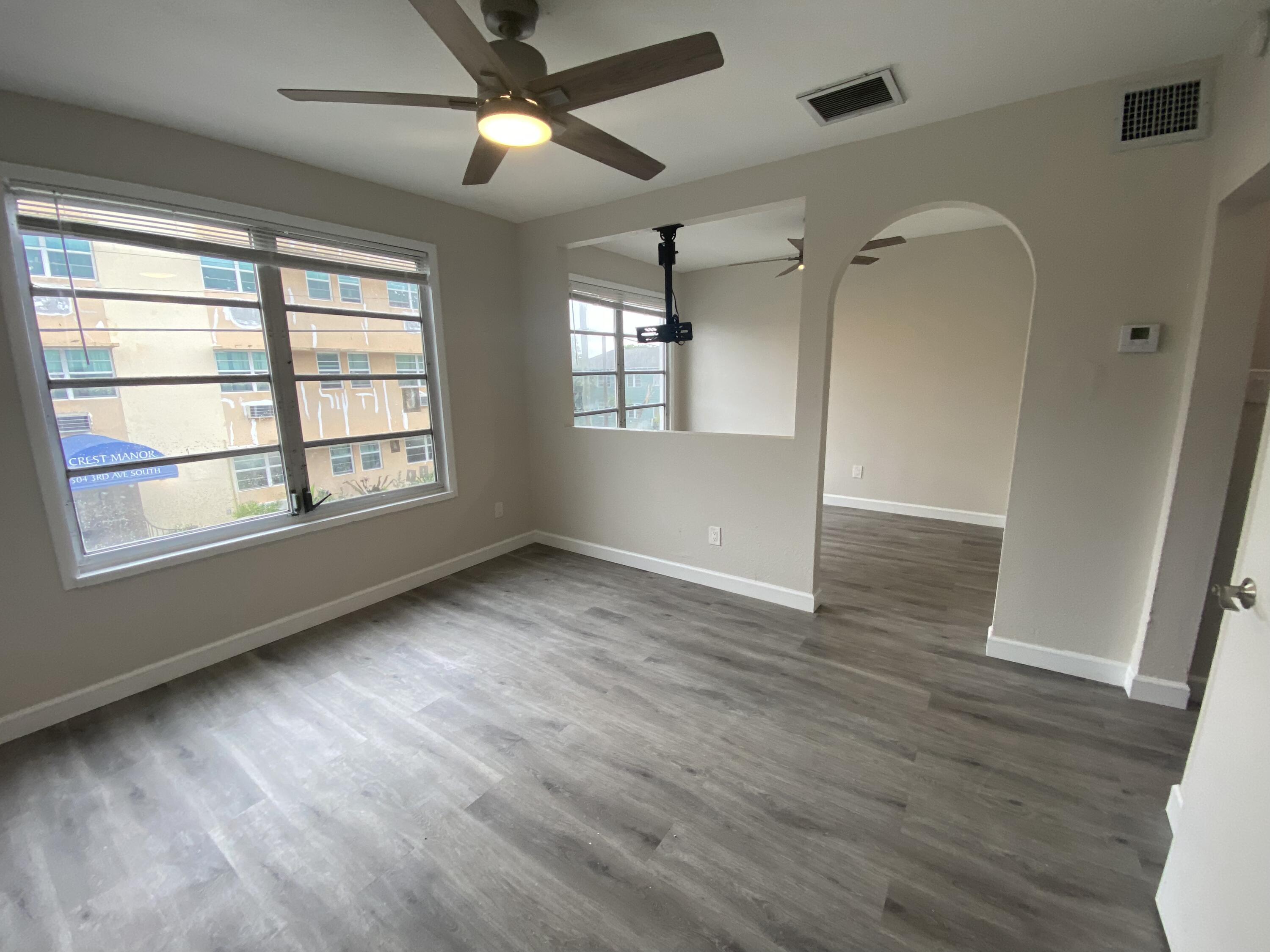 a view of an empty room with wooden floor and a window