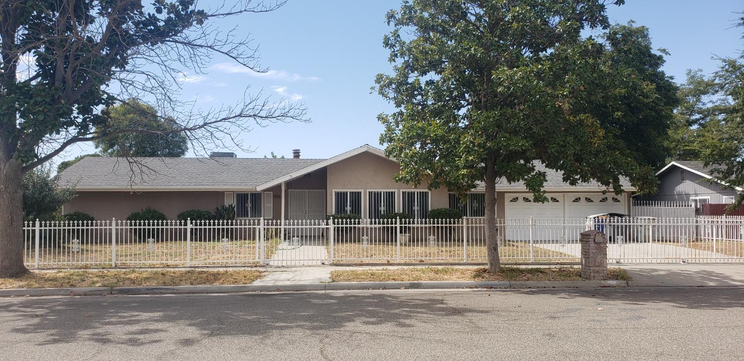 a view of a wooden house with large trees and wooden fence