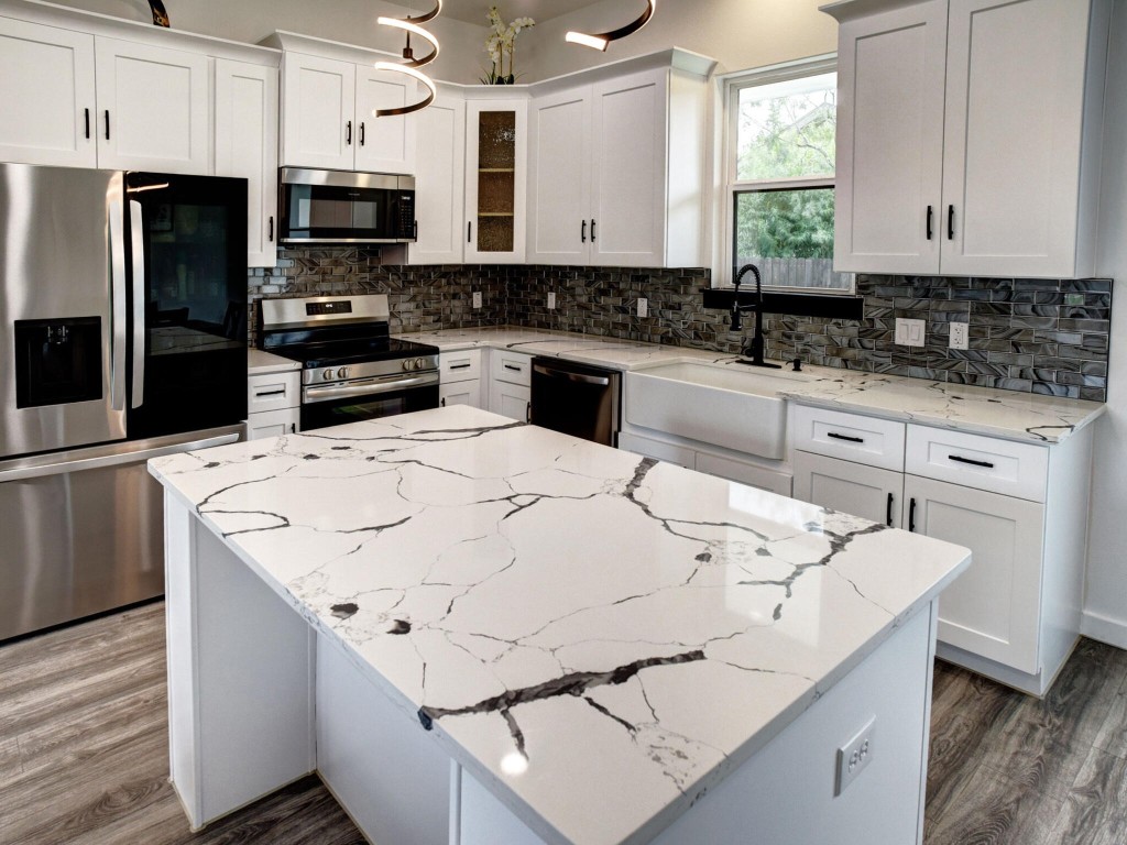 a kitchen with stainless steel appliances kitchen island a white counter space a sink a stove a microwave and cabinets