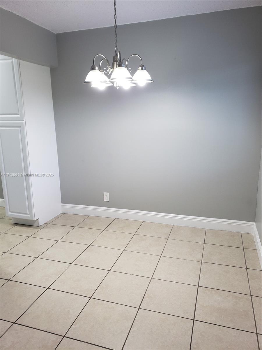 a view of an empty room with a chandelier fan