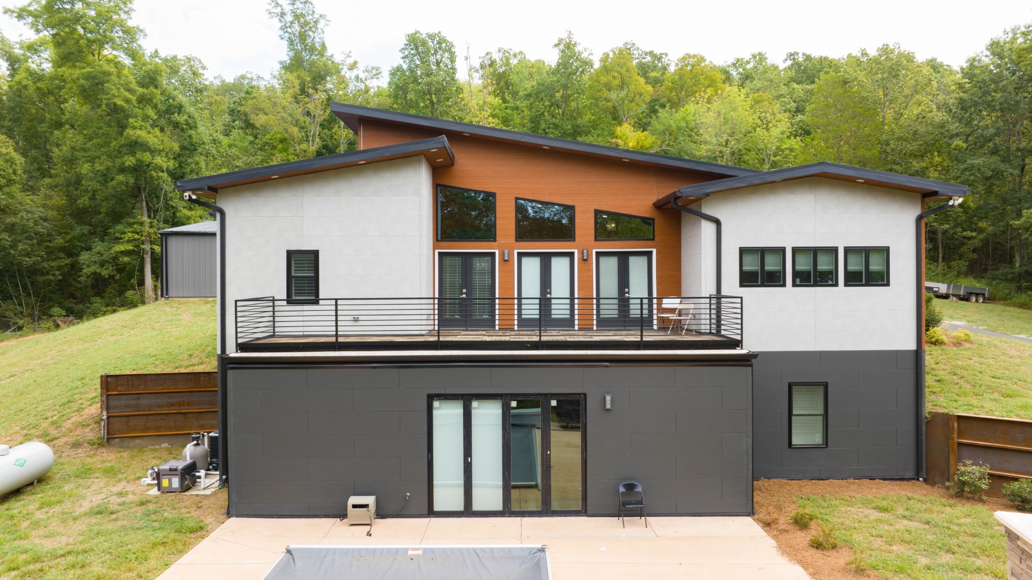 a backyard of a house with large trees and barbeque oven