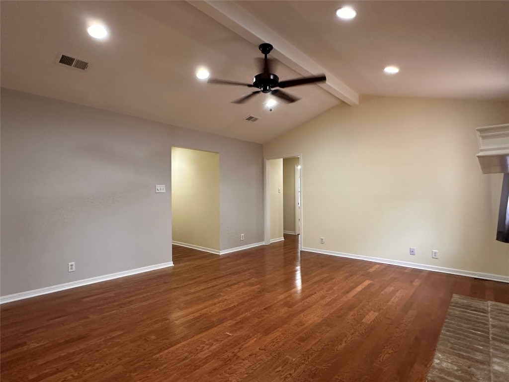 an empty room with wooden floor ceiling fan and windows