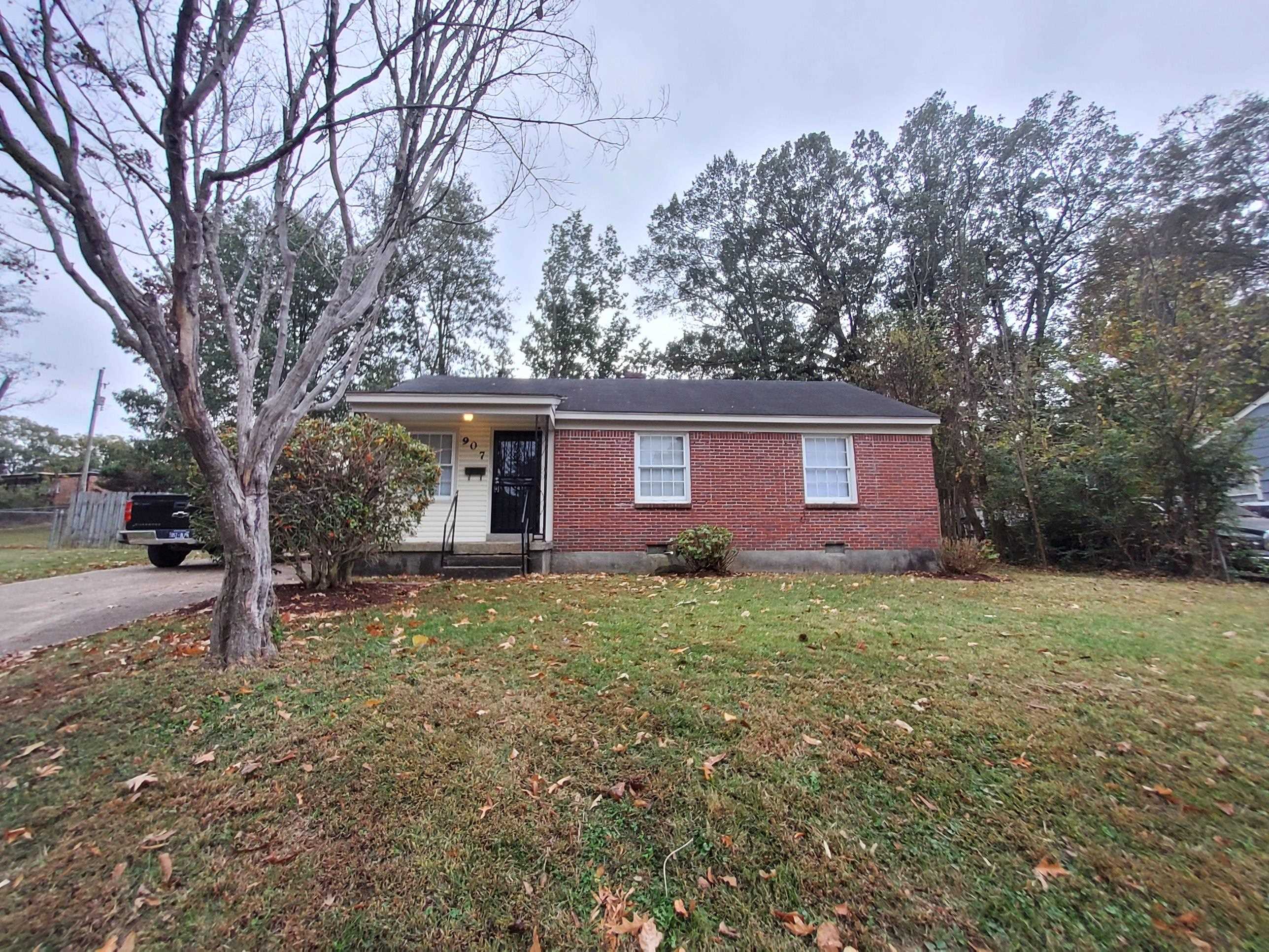 a view of a house with a yard and large tree