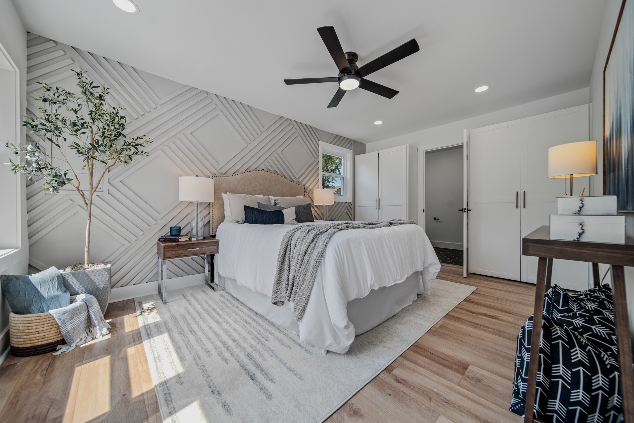 a spacious bedroom with a bed a chandelier and a chair