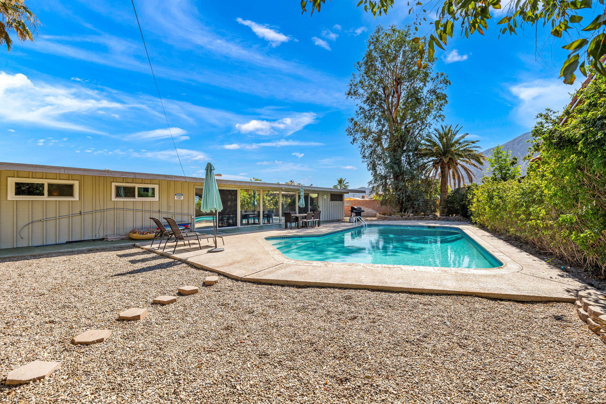 a view of a backyard with couches under an umbrella