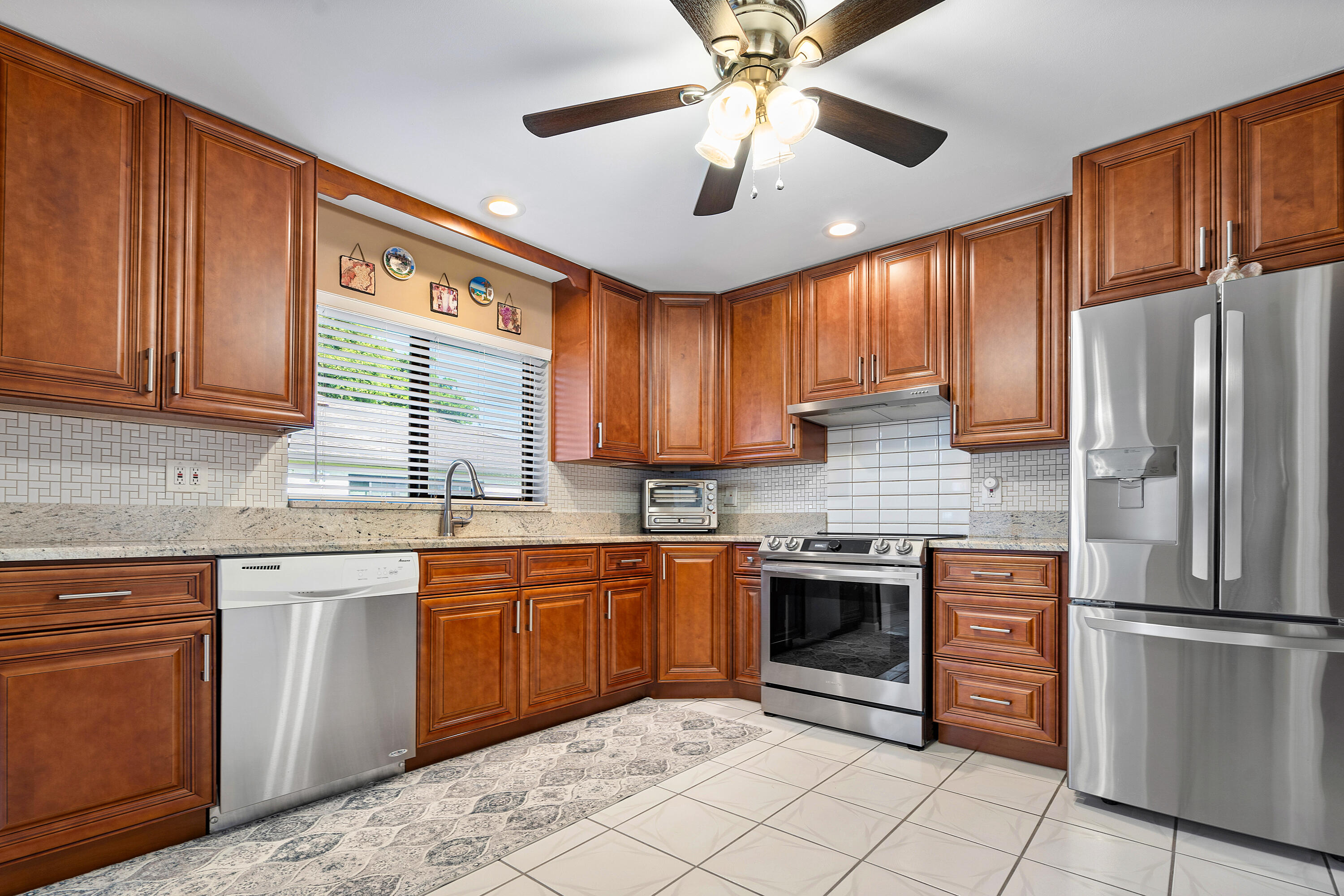 a kitchen with stainless steel appliances granite countertop a stove sink refrigerator and cabinets