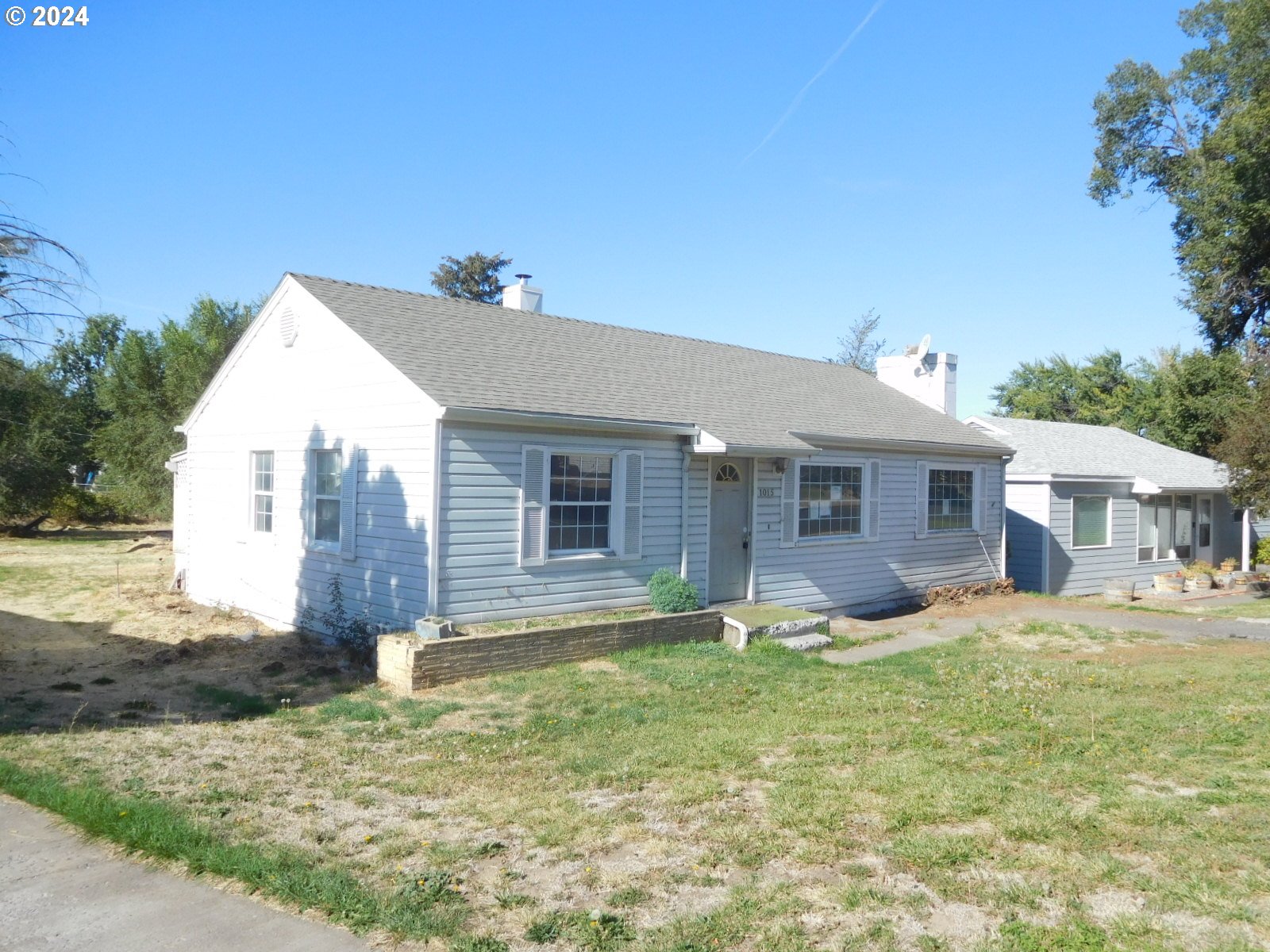 a front view of house with yard and trees in the background