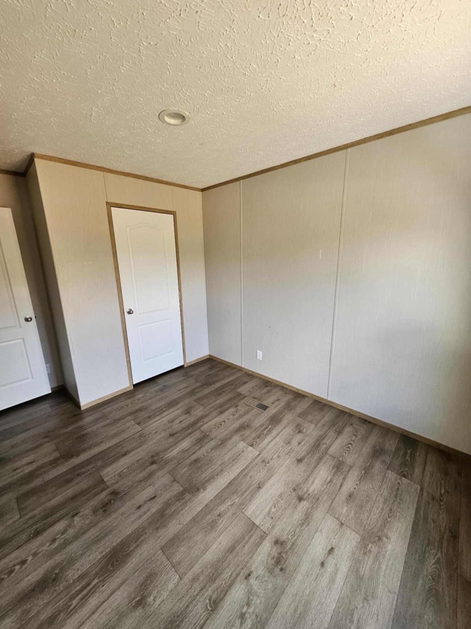 an empty room with wooden floor and mirror