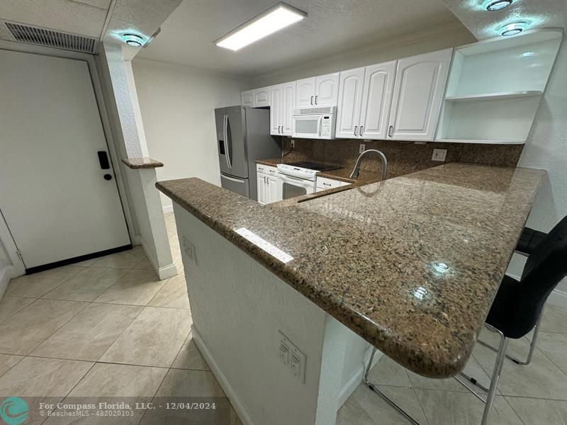 a kitchen with granite countertop a sink a stove and refrigerator