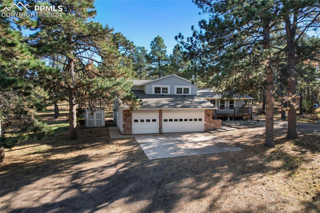 View of front of house featuring a shed, a wooden deck, and an oversized 3-car garage