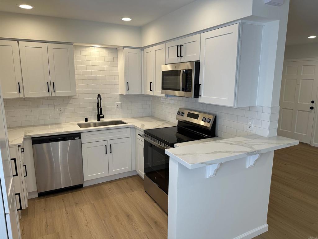 a kitchen with a sink a stove top oven and white cabinets