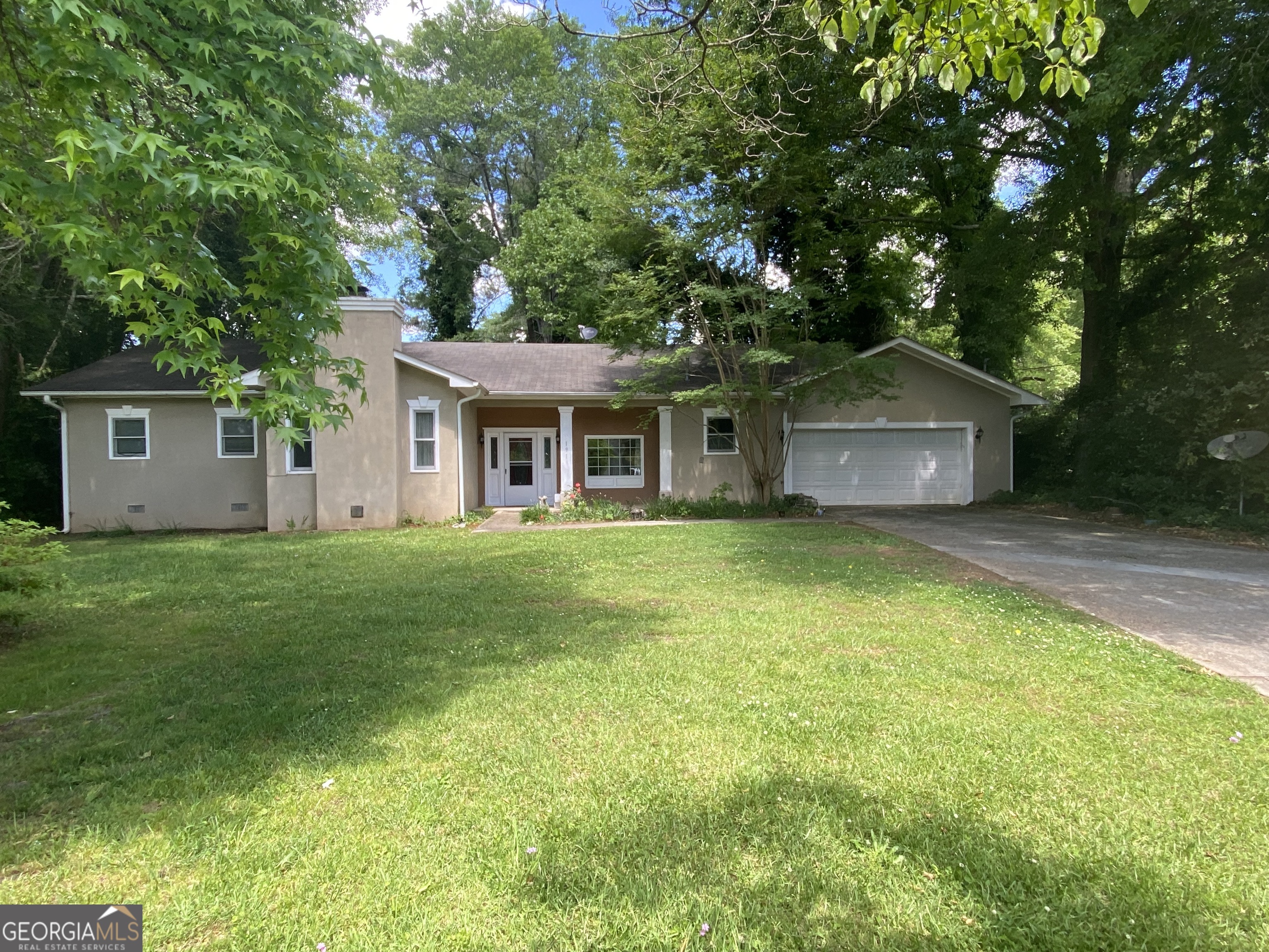 a front view of a house with a garden and trees