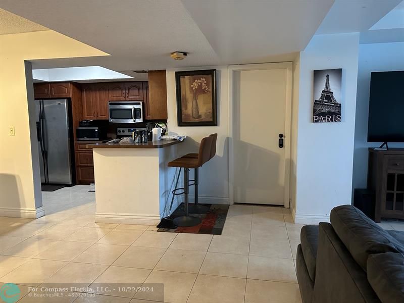 a living room with stainless steel appliances furniture a flat screen tv and a refrigerator