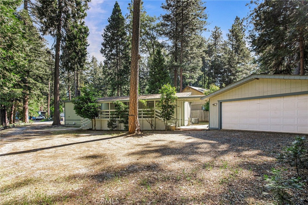 a view of a house with a small yard and large trees