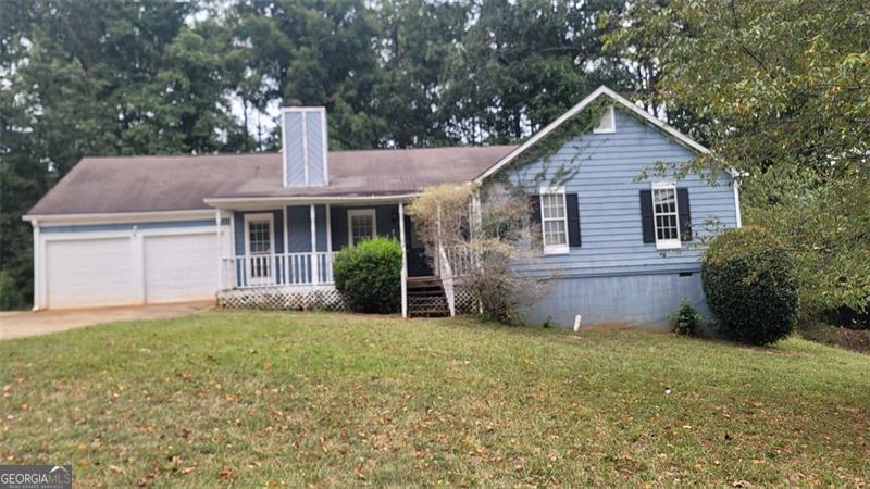 a front view of house with yard and trees in the background