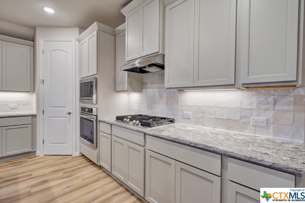 a kitchen with granite countertop a sink stainless steel appliances and cabinets