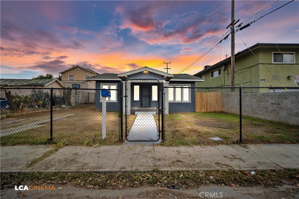 a view of a white house next to a yard with wooden fence