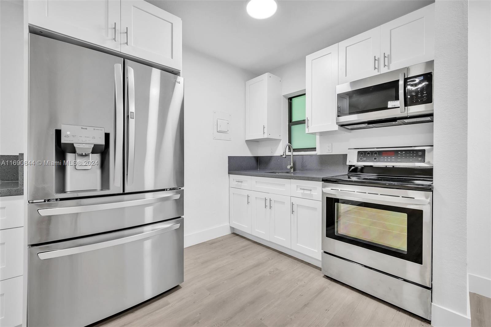 a kitchen with stainless steel appliances white cabinets and wooden floor