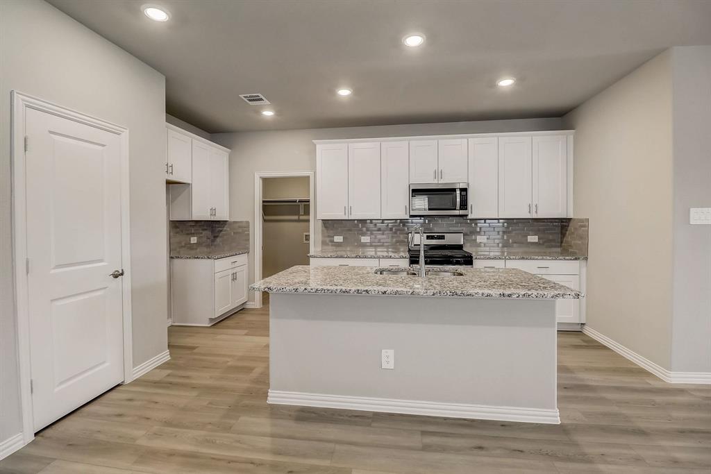 a large kitchen with stainless steel appliances granite countertop a stove a sink and a microwave