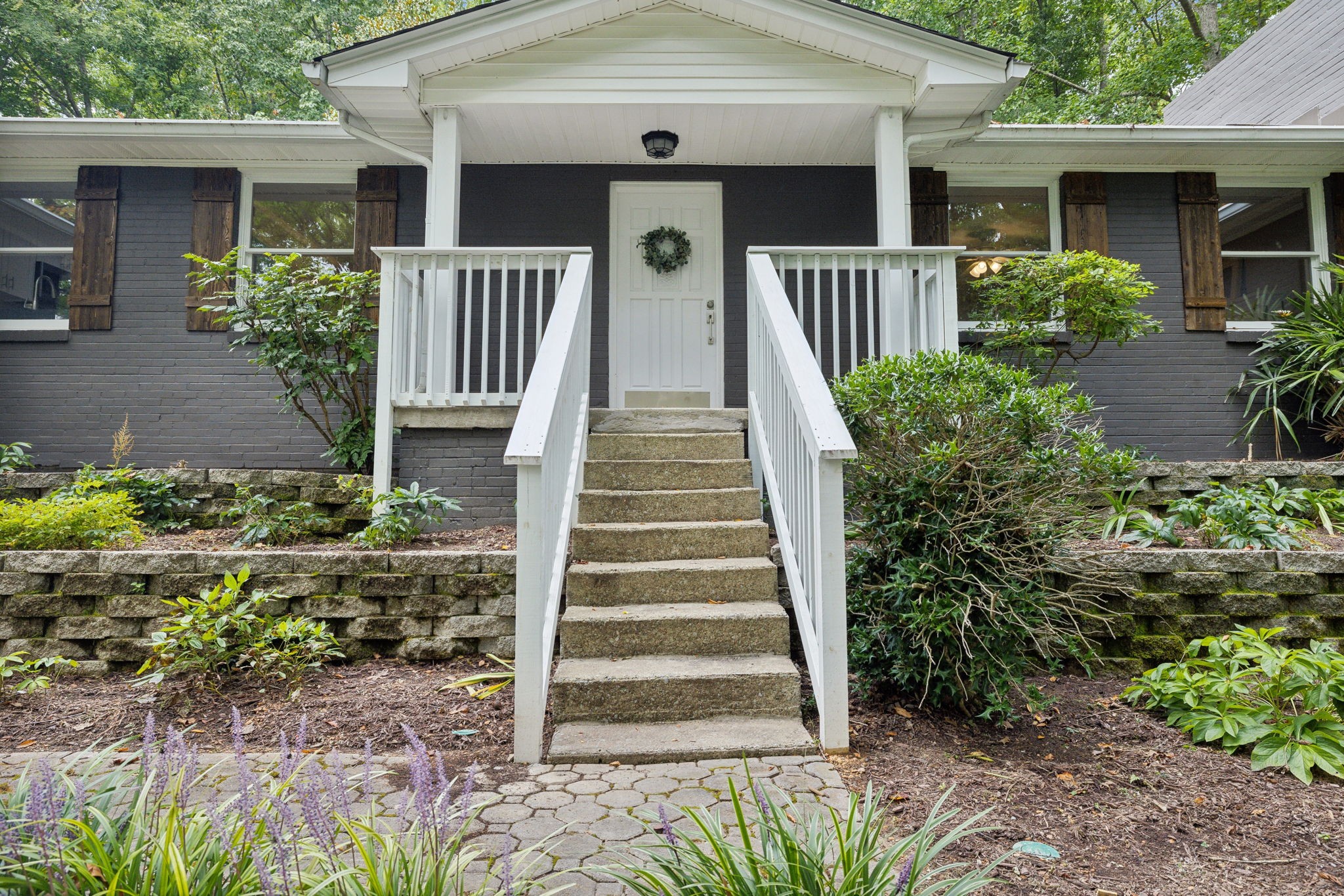 a front view of house with stairs and flowers