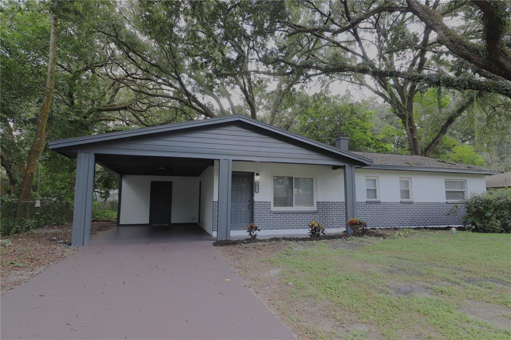 a view of a house with a yard and large tree