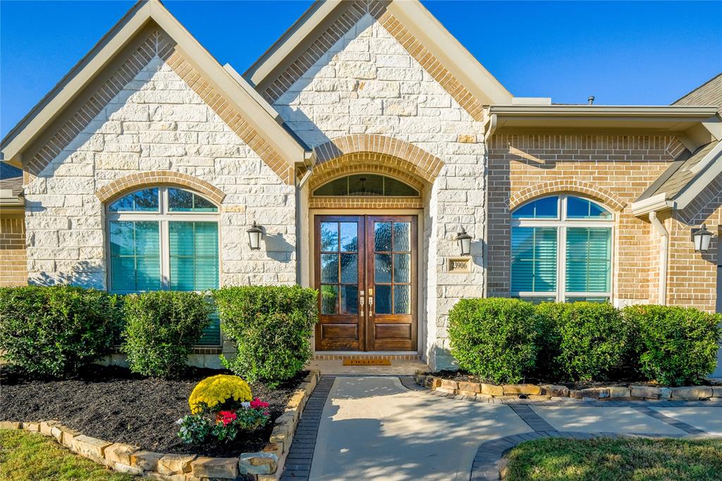 This is a single-story, brick-faced home with a three-car garage, well-manicured landscaping, and an inviting entryway.