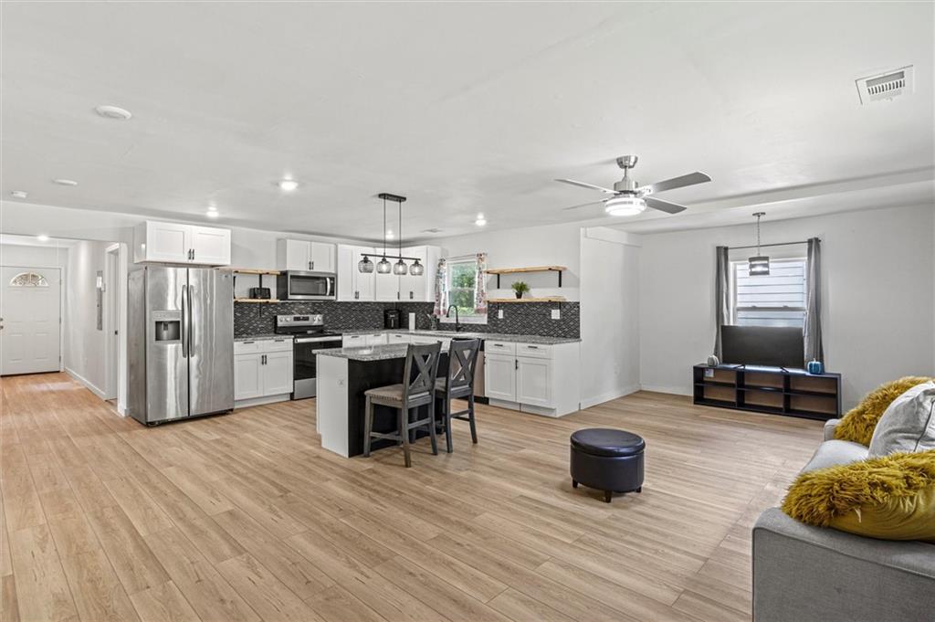 a kitchen with stainless steel appliances kitchen island sink refrigerator dining table and chairs