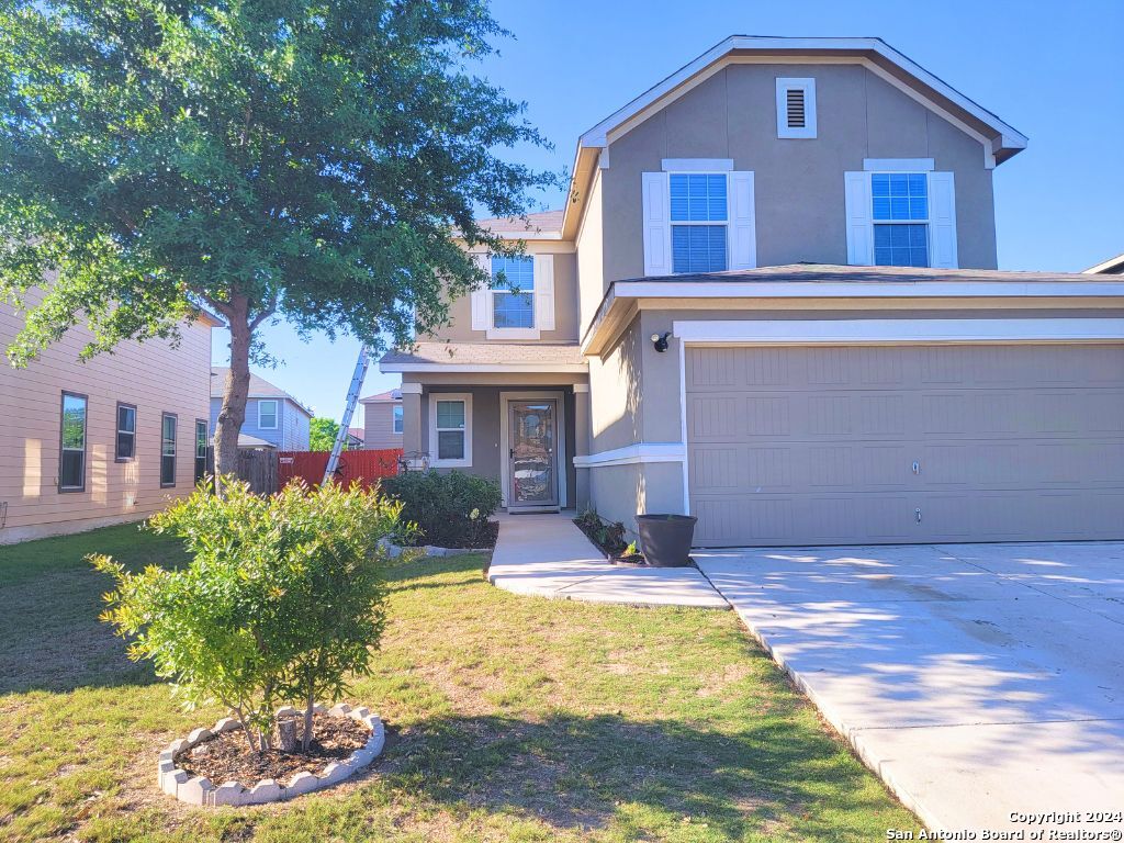 a front view of house with yard and trees in the background