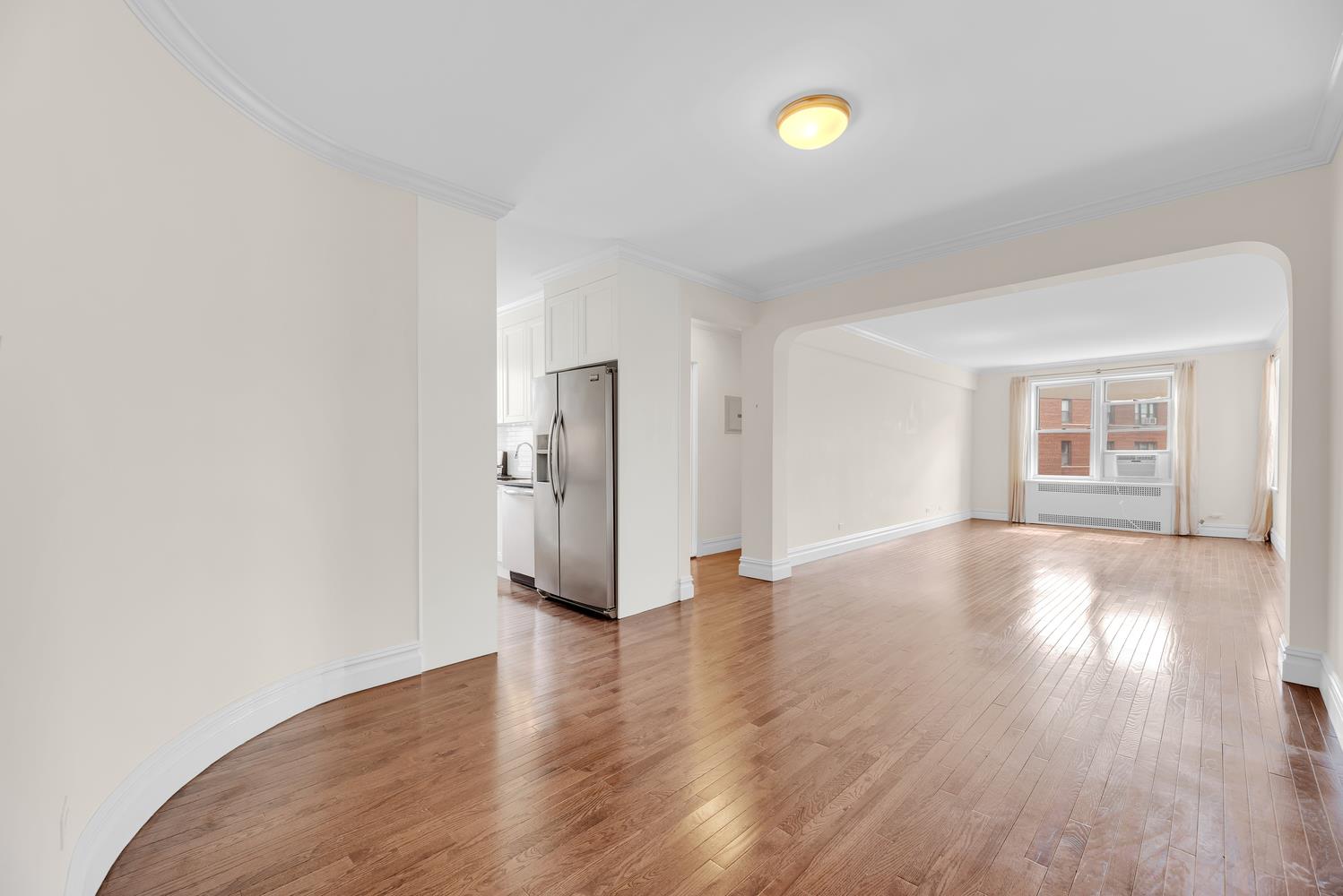 a view of an empty room with wooden floor and window