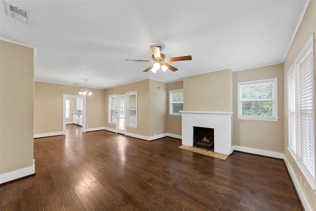 an empty room with wooden floor fireplace and windows