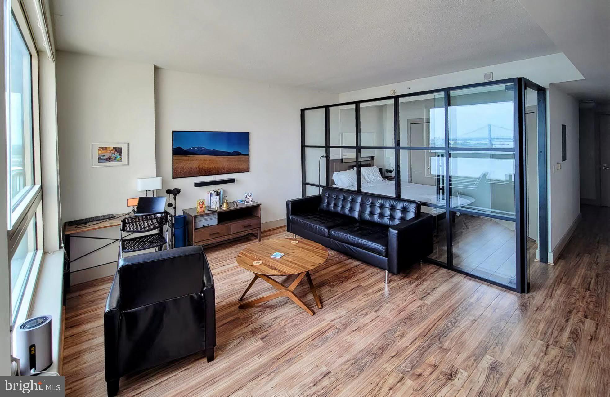 a living room with furniture a flat screen tv and a floor to ceiling window