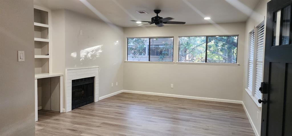 a view of an empty room with a fireplace and a window