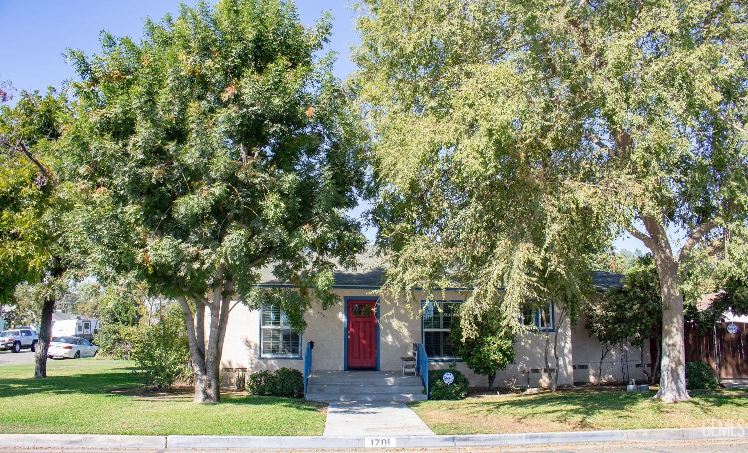 a front view of a house with a yard and large trees