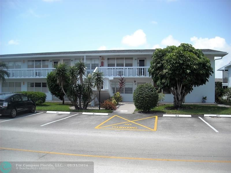 front view of a house with potted plants and palm trees