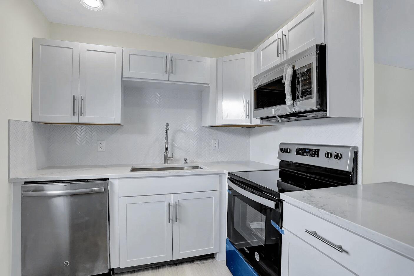 a kitchen with stainless steel appliances granite countertop grey cabinets a stove a microwave and a sink