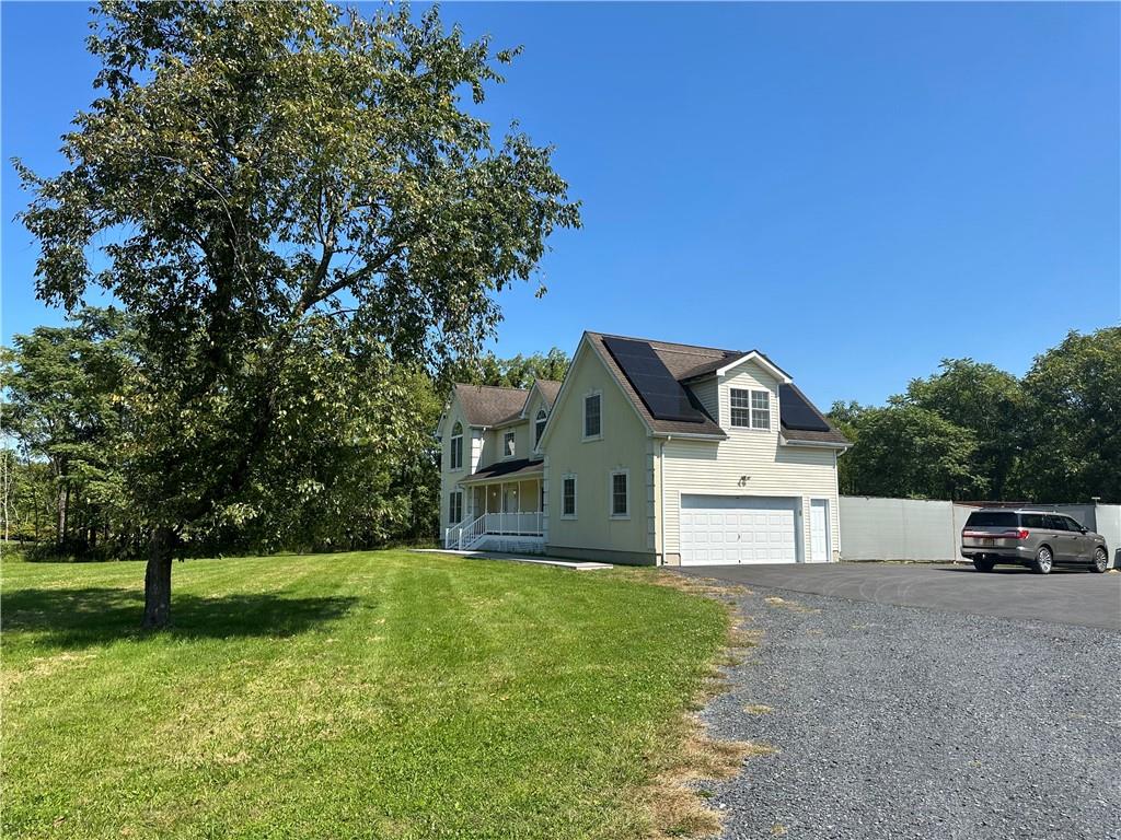 View of home's exterior with a yard, a garage, and a porch