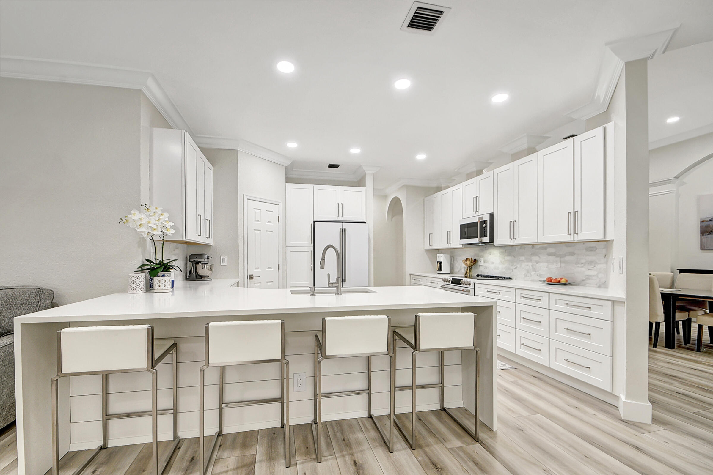 a kitchen with stainless steel appliances kitchen island granite countertop a table chairs sink and cabinets