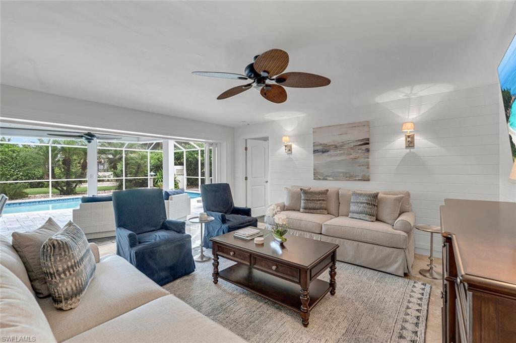 a living room with furniture ceiling fan and a large window