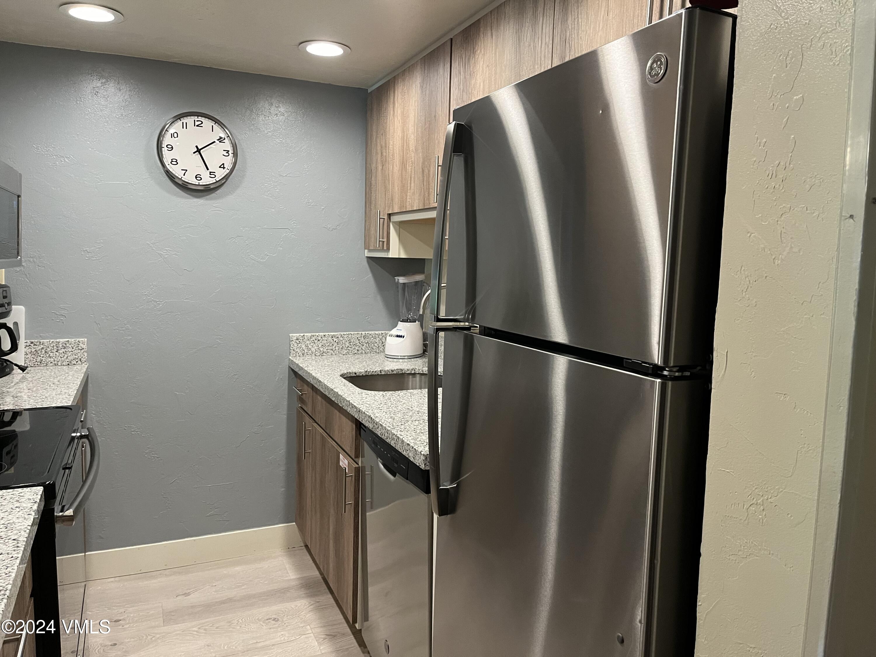 a view of a refrigerator in kitchen and stainless steel appliances wooden floor