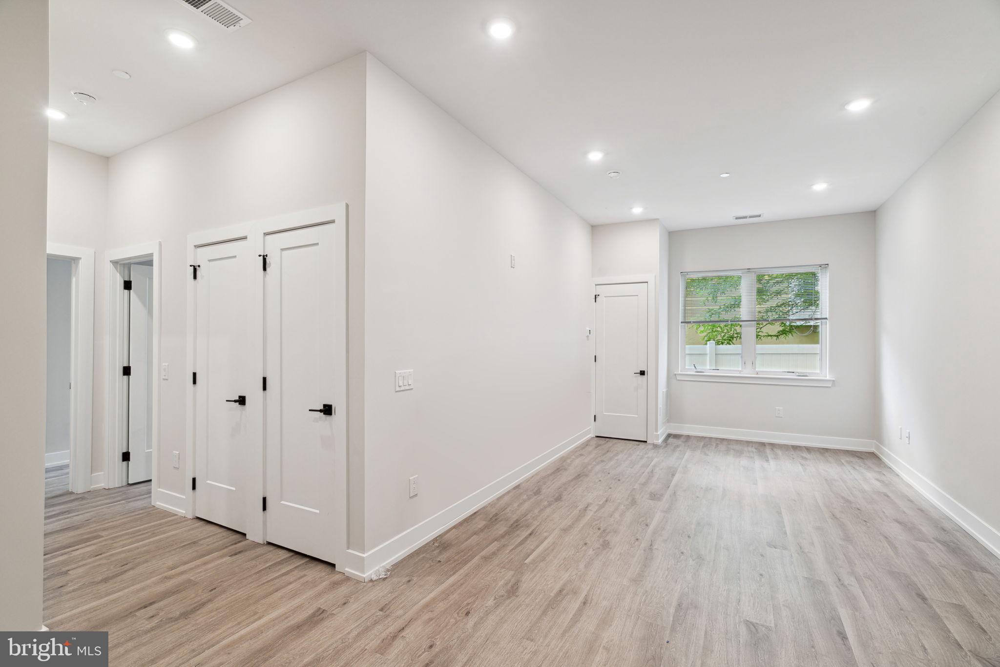 a view of an empty room with wooden floor and window