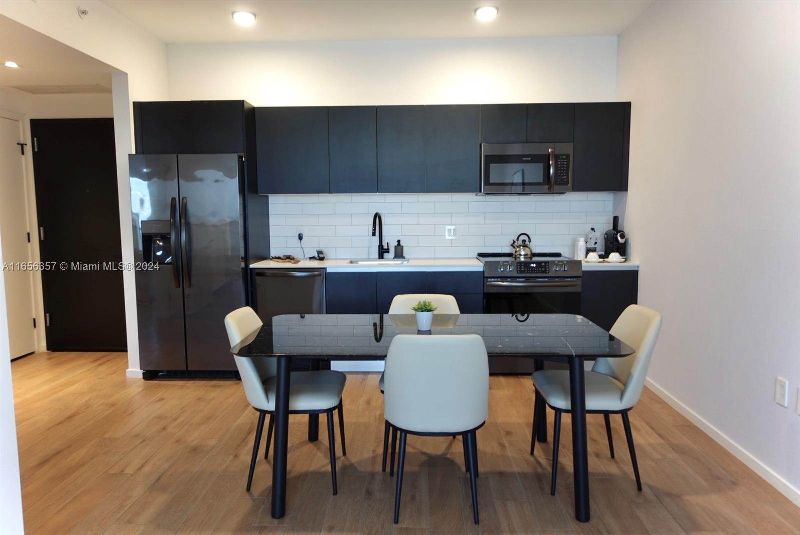 a kitchen with granite countertop a dining table chairs and a refrigerator