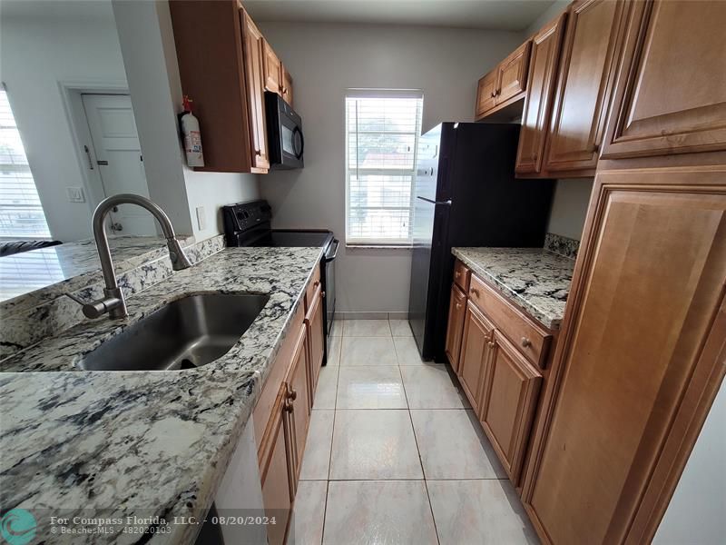 a kitchen with granite countertop a refrigerator stove and sink