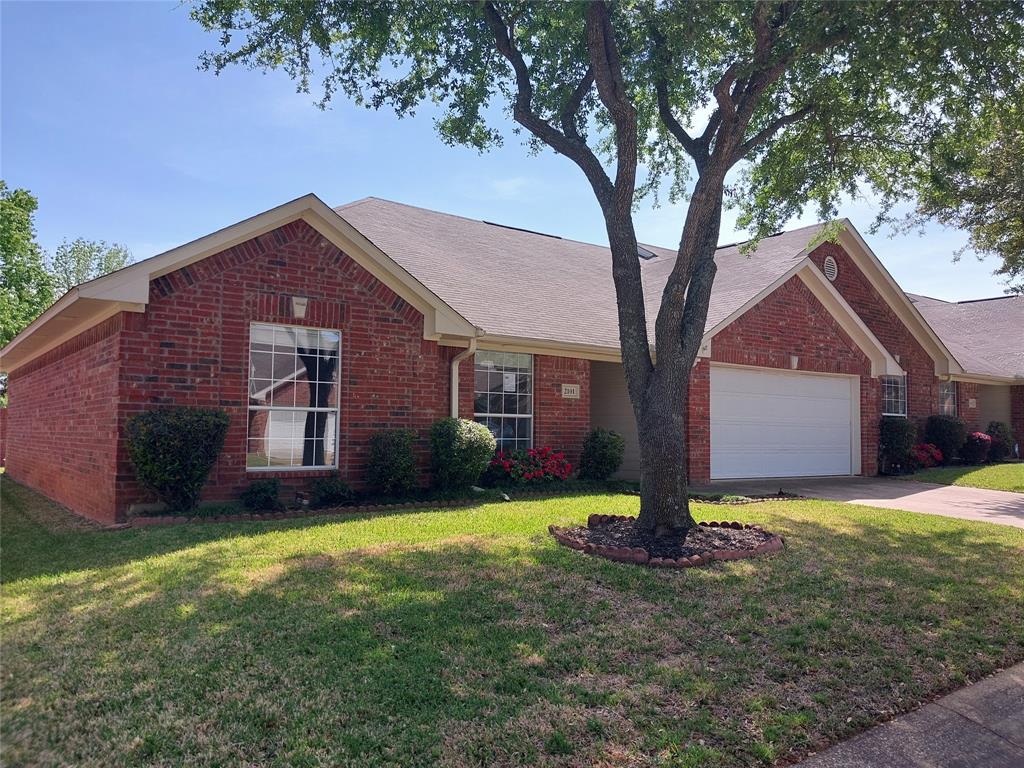 a front view of a house with a yard and large tree