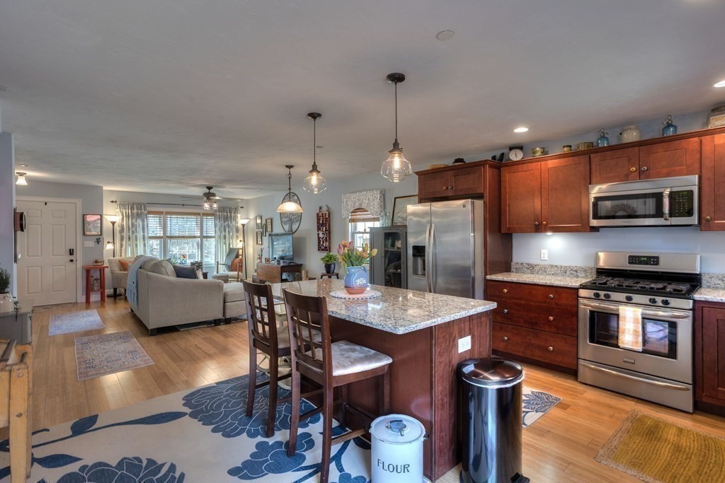 a kitchen with stainless steel appliances granite countertop a table chairs and a refrigerator