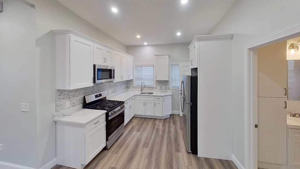 a kitchen with a sink a counter top space stainless steel appliances and cabinets