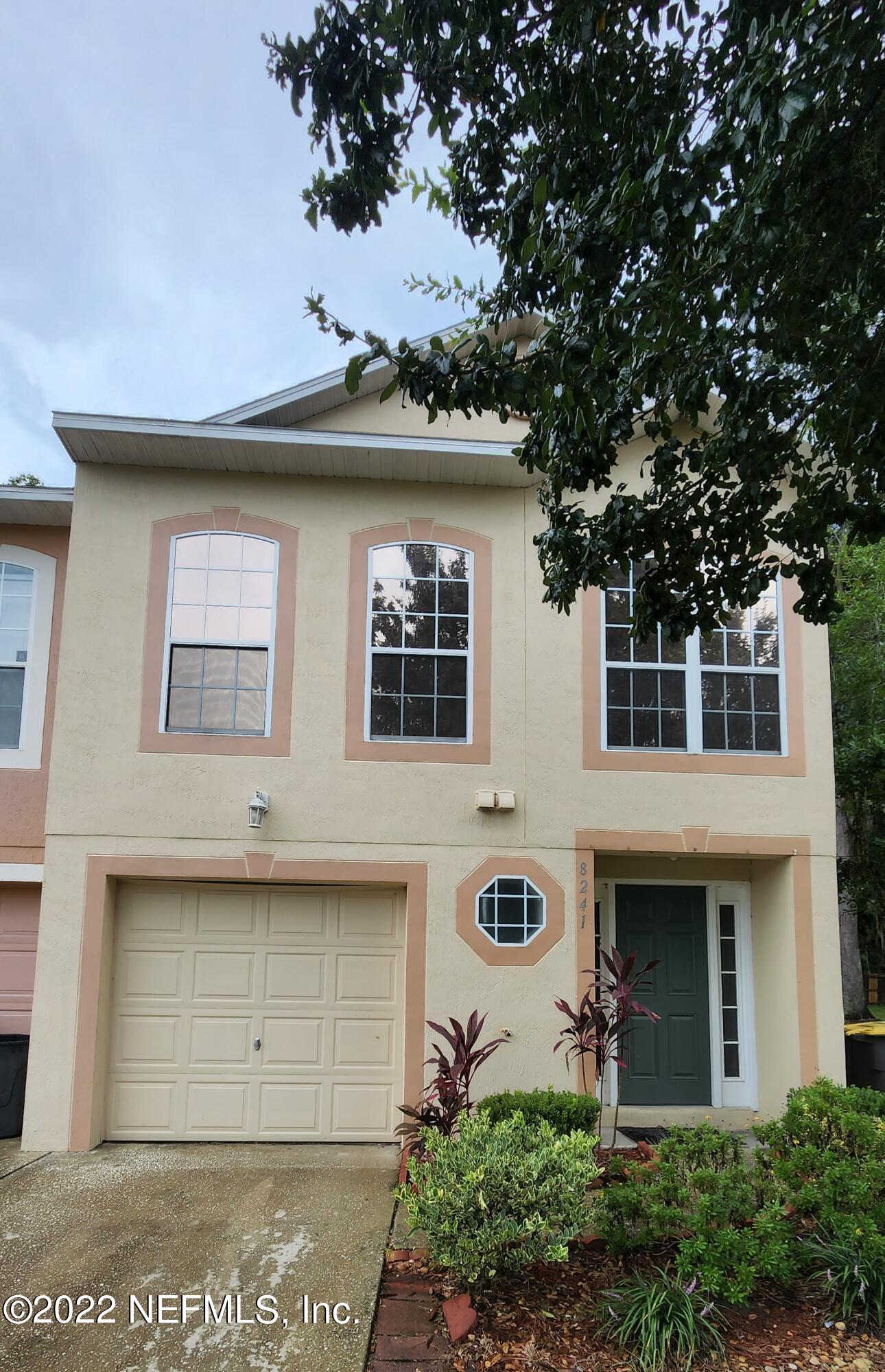 a front view of a house with a tree