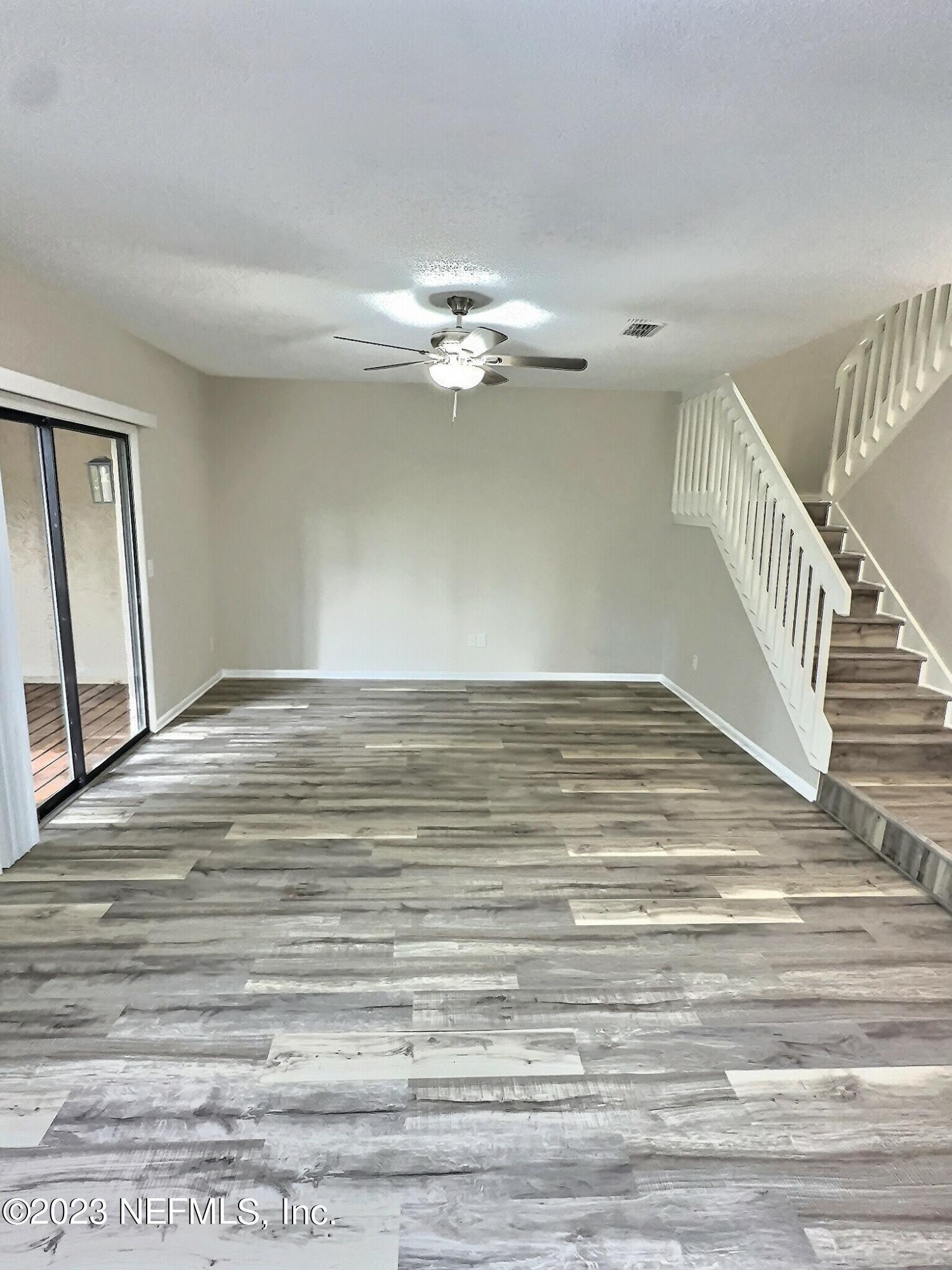 a view of a room with wooden floor and ceiling fan