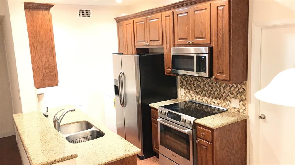 a kitchen with granite countertop a sink stove and refrigerator