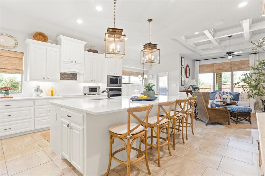 a kitchen with stainless steel appliances kitchen island granite countertop a table chairs sink and white cabinets