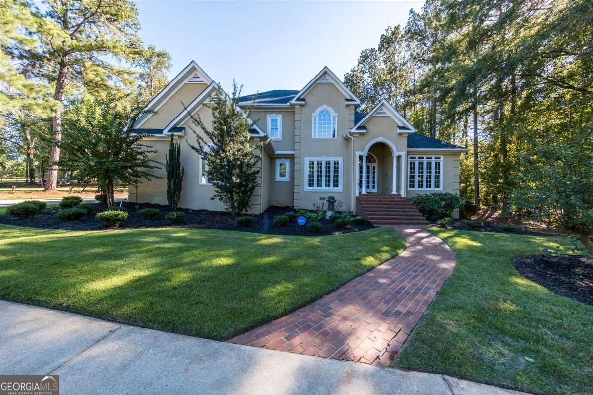 a front view of a house with a garden and trees